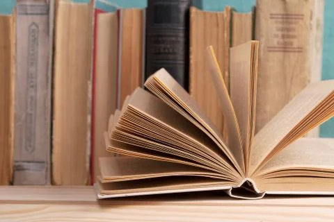 Open book, stack of hardback books on wooden table Foto stock