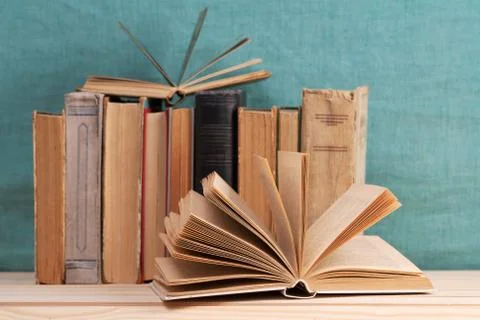 Open book, stack of hardback books on wooden table Stock Photos