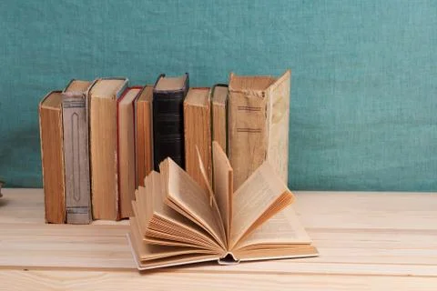 Open book, stack of hardback books on wooden table Stock Photos