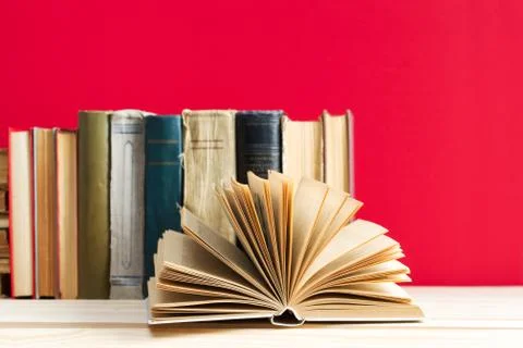 Open book, stack of hardback books on wooden table Stock Photos