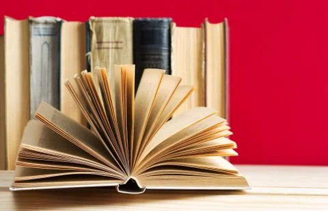 Open book, stack of hardback books on wooden table Foto stock