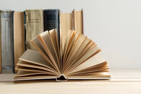 Open book, stack of hardback books on wooden table Stock Photos