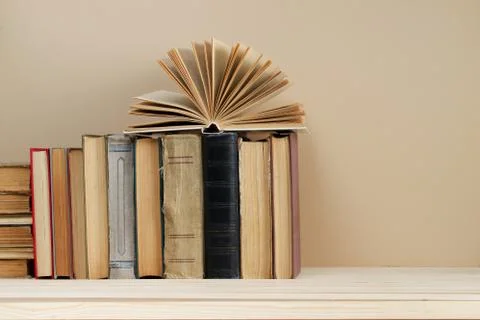 Open book, stack of hardback books on wooden table Stock Photos
