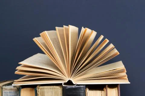 Open book, stack of hardback books on wooden table Stock Photos