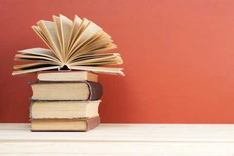 Open book, stack of hardback books on wooden table Stock Photos