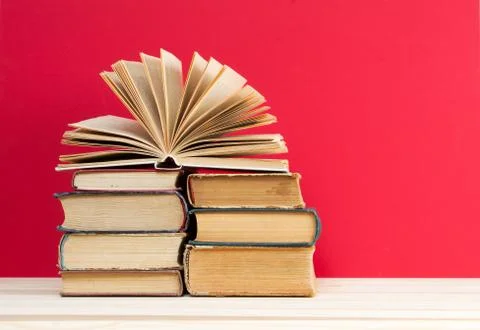 Open book, stack of hardback books on wooden table Stock Photos