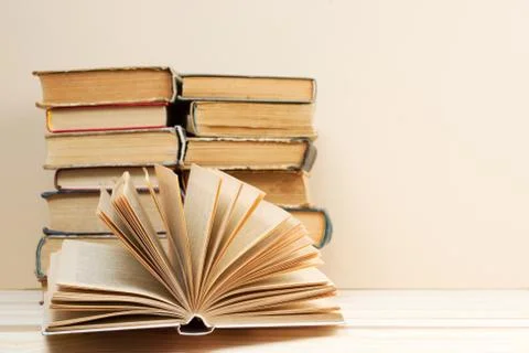 Open book, stack of hardback books on wooden table Stock Photos