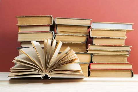 Open book, stack of hardback books on wooden table Stock Photos