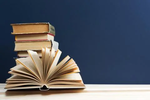 Open book, stack of hardback books on wooden table 스톡 사진