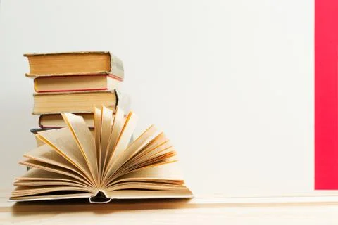 Open book, stack of hardback books on wooden table Stock Photos