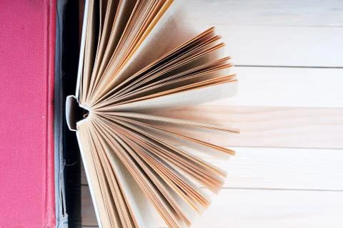 Open book, stack of hardback books on wooden table Stock Photos