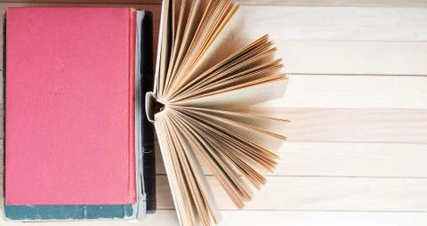 Open book, stack of hardback books on wooden table Stock Photos