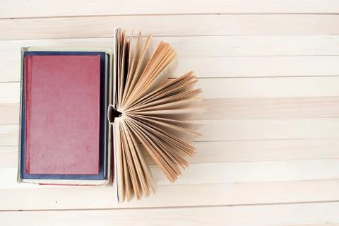 Open book, stack of hardback books on wooden table Stock Photos