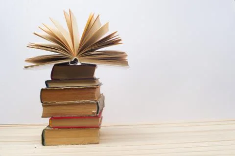 Open book, stack of hardback books on wooden table Foto stock