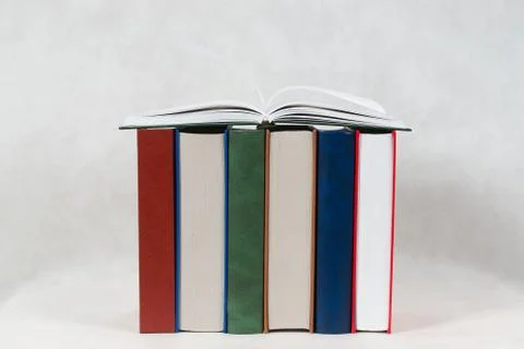 Open book, stack of hardback books on wooden table Stock Photos
