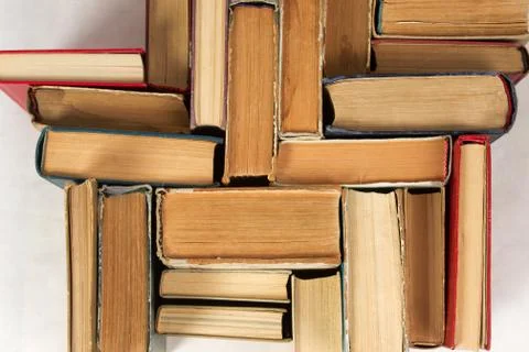 Open book, stack of hardback books on table. Top view Stock Photos