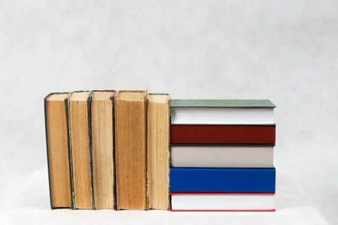 Open book, stack of hardback books on table Stock Photos