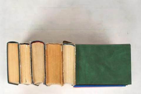 Open book, stack of hardback books on table. Top view Stock Photos