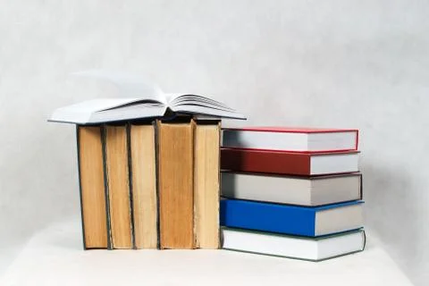 Open book, stack of hardback books on table Stock Photos