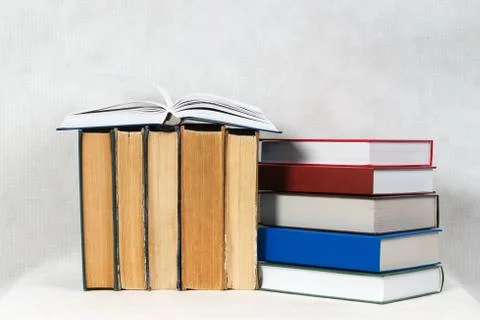 Open book, stack of hardback books on table Stock Photos