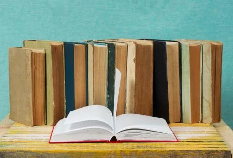 Open book, stack of hardback books on wooden table Stock Photos