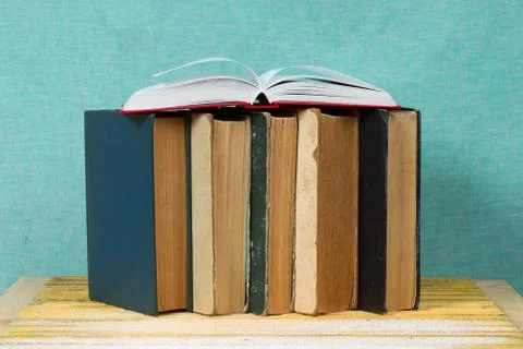 Open book, stack of hardback books on wooden table Stock Photos