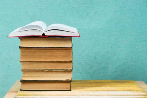 Open book, stack of hardback books on wooden table Foto stock