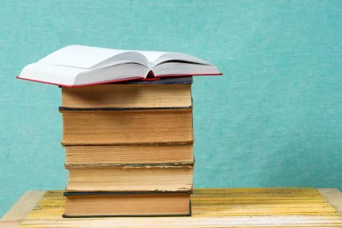 Open book, stack of hardback books on wooden table Stock Photos