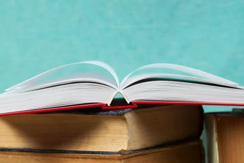 Open book, stack of hardback books on wooden table Stock Photos