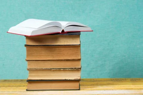 Open book, stack of hardback books on wooden table Foto stock