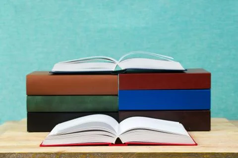 Open book, stack of hardback books on wooden table Stock Photos