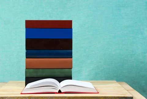 Open book, stack of hardback books on wooden table Stock Photos