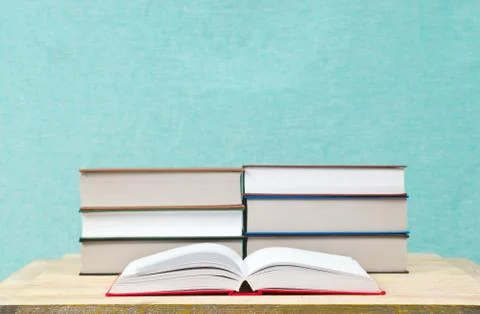 Open book, stack of hardback books on wooden table Stock Photos