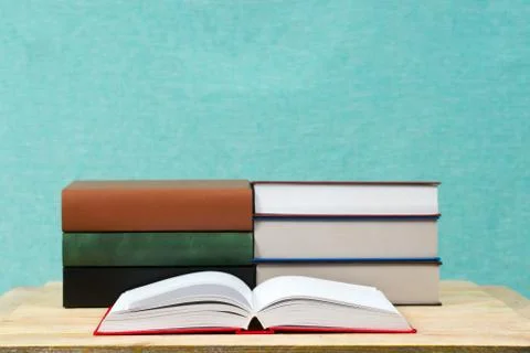 Open book, stack of hardback books on wooden table Stock Photos