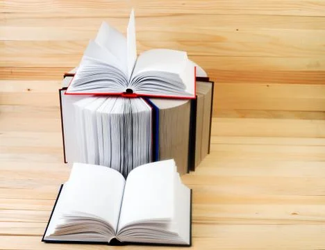 Open book, stack of hardback books on wooden table Stock Photos