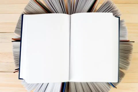 Open book, stack of hardback books on wooden table Stock Photos