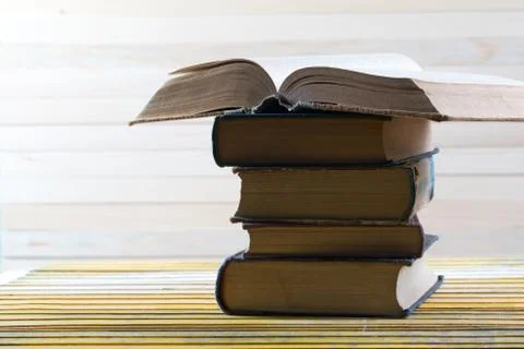 Open book, stack of hardback books on wooden table Stock Photos