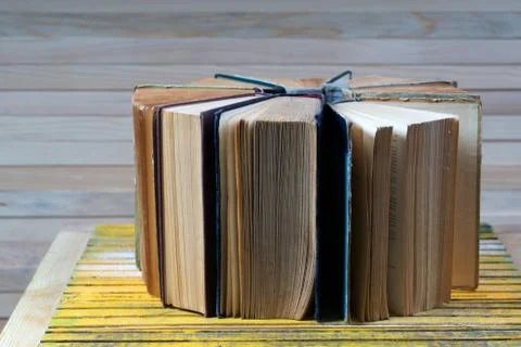 Open book, stack of hardback books on wooden table Foto stock