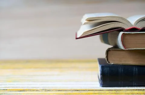 Open book, stack of hardback books on wooden table Stock Photos