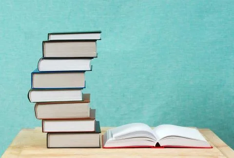Open book, stack of hardback books on wooden table Stock Photos
