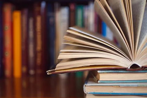 Open book on a stack of other books in library Stock Photos