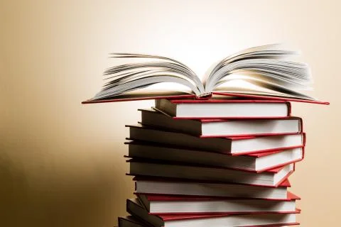 An open book on a stack of red books in the form of a spiral. Stock Photos