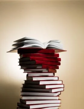 An open book on a stack of red books in the form of a spiral. Stock Photos