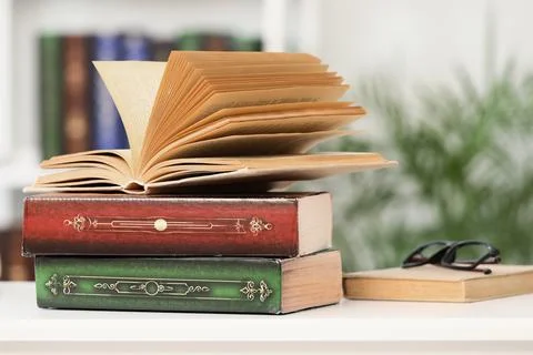 Open book on stack of vintage books with reading glasses, education and knowl Stock Photos