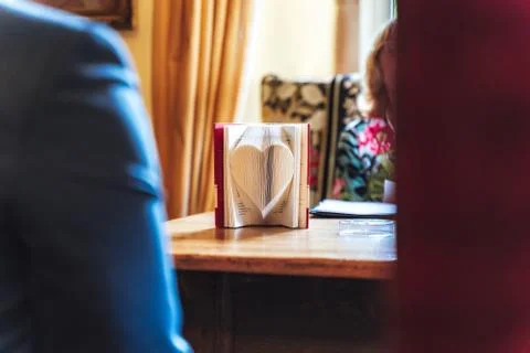 Open book standing on table. Book pages folded to heart shape. Symbol of love. Stock Photos