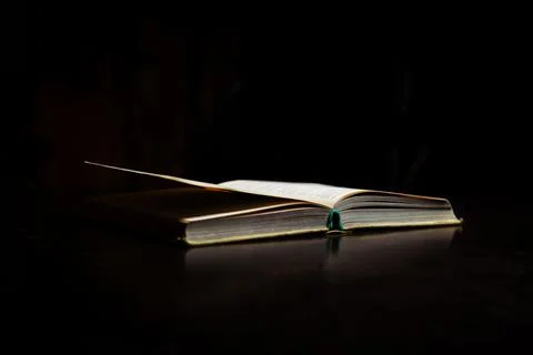 An open book on the table. Black background. Learning, reading concept. Stock Photos