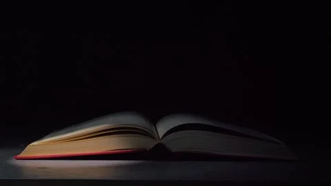 An open book on a table in a dark studio. A beam of light from the searchlight Stock Footage 251049917