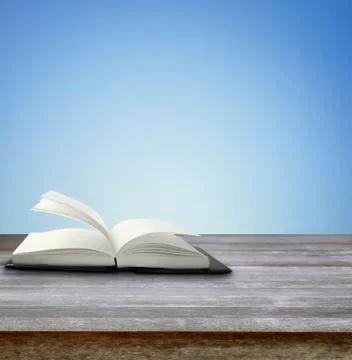 Open book on table in front of blue background Stock Photos