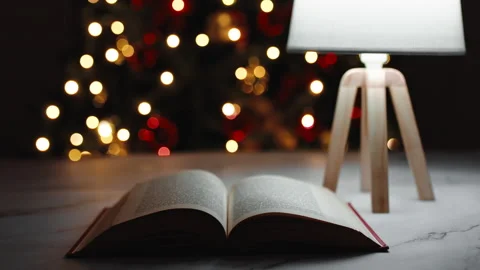 Open book on a table in front of Christmas tree during night Stock Footage 220615189