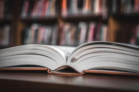 Open book on the table in a library and bookshelf Foto stock